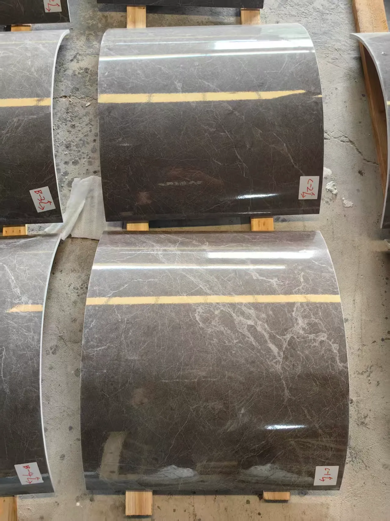 Multiple polished dark sintered stone panels formed into consistent curves using hot bending technology.