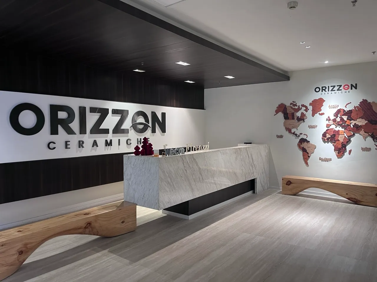 Orizzon Ceramiche showroom reception in Foshan featuring a stone-look counter and global market display.