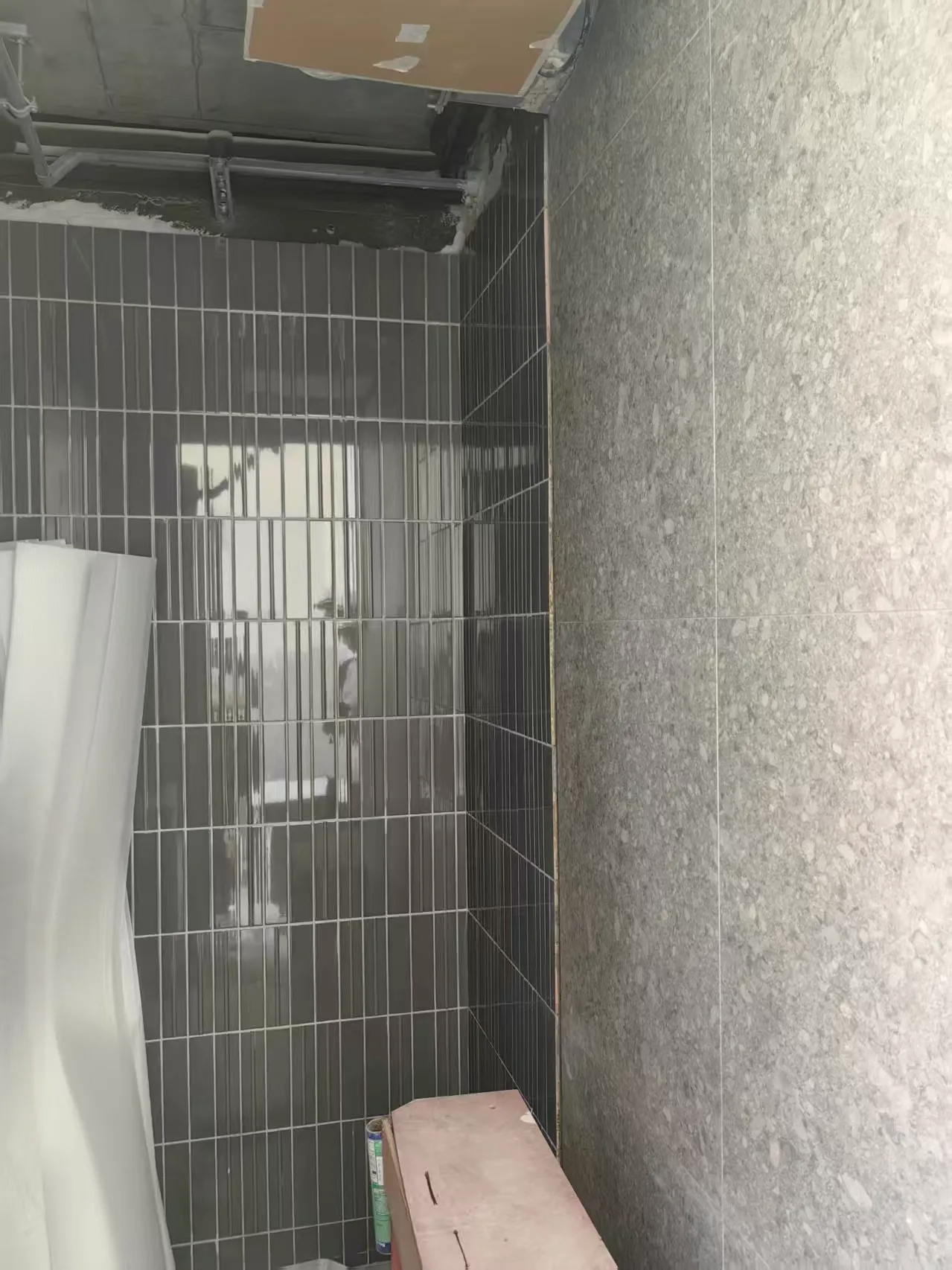 Glossy green rectangular wall tiles paired with large-format grey terrazzo-look tiles in a residential interior.