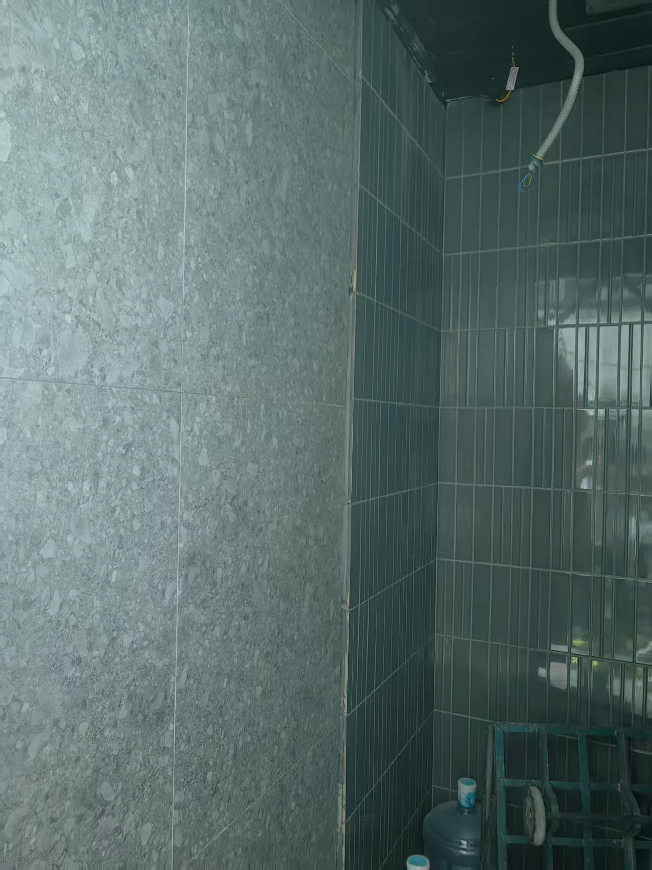 Grey terrazzo-look matte tiles combined with glossy green rectangular wall tiles in a Hong Kong residential interior.